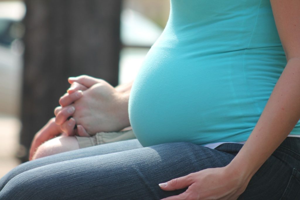 raskaana oleva nainen istuu ja pitää kädestä